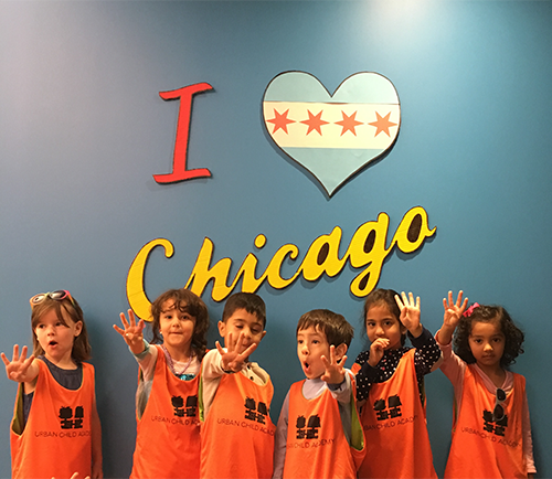 Photo of a group if kids holding up four fingers each in front of a I love Chicago sign.